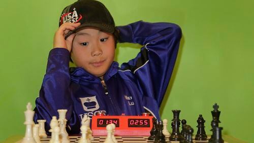 Maximillian Lu adjusts his cap as he toys with a chess set during an interview, Monday, Nov. 16, 2015, in Armonk, N.Y. The 10-year-old recently became the youngest chess master ever in the United States. (AP Photo/Julie Jacobson)