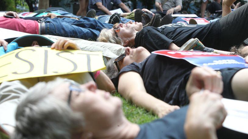 Demonstrators lie on the ground Friday at Woodruff Park during a “die-in” protest in opposition to the National Rifle Association’s convention in Atlanta. They also protested against President Donald Trump, who spoke at the convention Friday. (HENRY TAYLOR / HENRY.TAYLOR@AJC.COM)