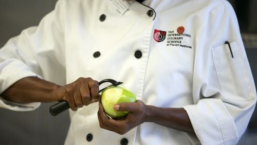 A student peels an apple to make dinner in the kitchen at the Art Institute of Atlanta in 2016. AJC FILE PHOTO