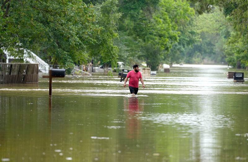 A man walks through floodwaters on River Oaks Drive, Saturday, May 4, 2024, in Woodlock, Texas. (/Houston Chronicle via AP)