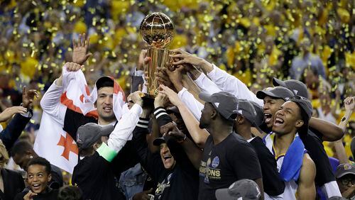 Golden State Warriors players, coaches and owners hold up the Larry O'Brien NBA Championship Trophy after Game 5 of basketball's NBA Finals between the Warriors and the Cleveland Cavaliers in Oakland, Calif., Monday, June 12, 2017. The Warriors won 129-120 to win the NBA championship. (AP Photo/Marcio Jose Sanchez)