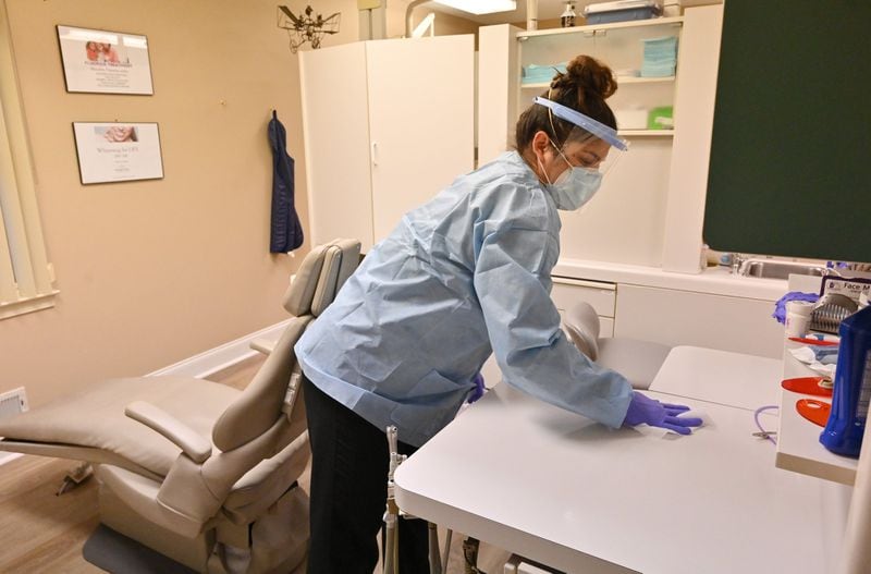 Adriana Sarti, an assistant at Windy Hill Dentistry, uses a disinfectant wipe to sanitize the treatment room after a patient left. While dentists for decades have worn masks and gloves when treating patients, the coronavirus pandemic has led to even stricter infection-control measures. (Hyosub Shin / Hyosub.Shin@ajc.com)