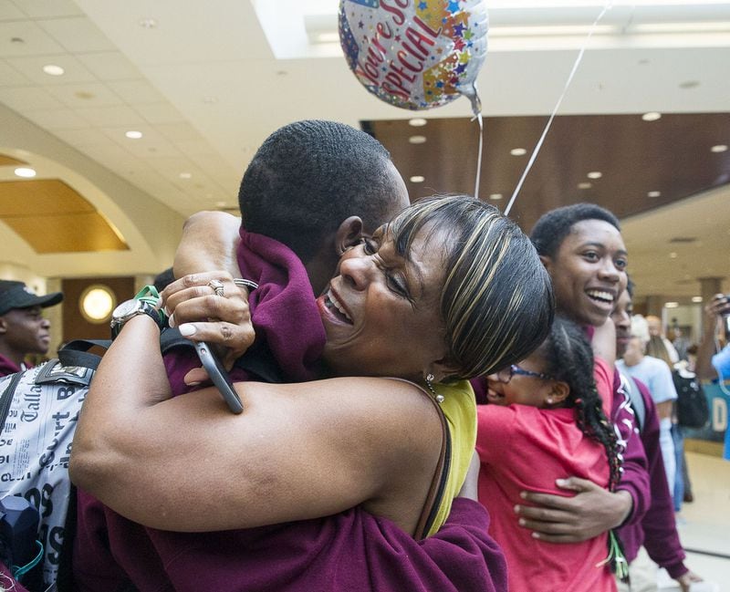 7/12/2019 — Atlanta, Georgia — Millicent Roman (center) hugs her son, Don Jr. Roman, as he and members of the Harvard Diversity Project arrive to the domestic terminal at Hartsfield Jackson International Airport in Atlanta, Friday, July 12, 2019. The group, an Atlanta-based pipeline of the Harvard Debate Council, returned to Atlanta as champions of Harvard University’s annual international debate tournament. Don Jr. Roman, a student at North Atlanta High School, was one of two students that returned with an unprecedented, undefeated record. (Alyssa Pointer/alyssa.pointer@ajc.com)
