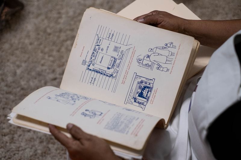 Atlanta-based Sarahn Henderson, who has been a midwife for 41 years and has extensively researched the history of Black midwives in the South, looks through an illustrated “Manual for Midwives” textbook once used by the Georgia Department of Public Health. (Ben Gray for The Atlanta Journal-Constitution)