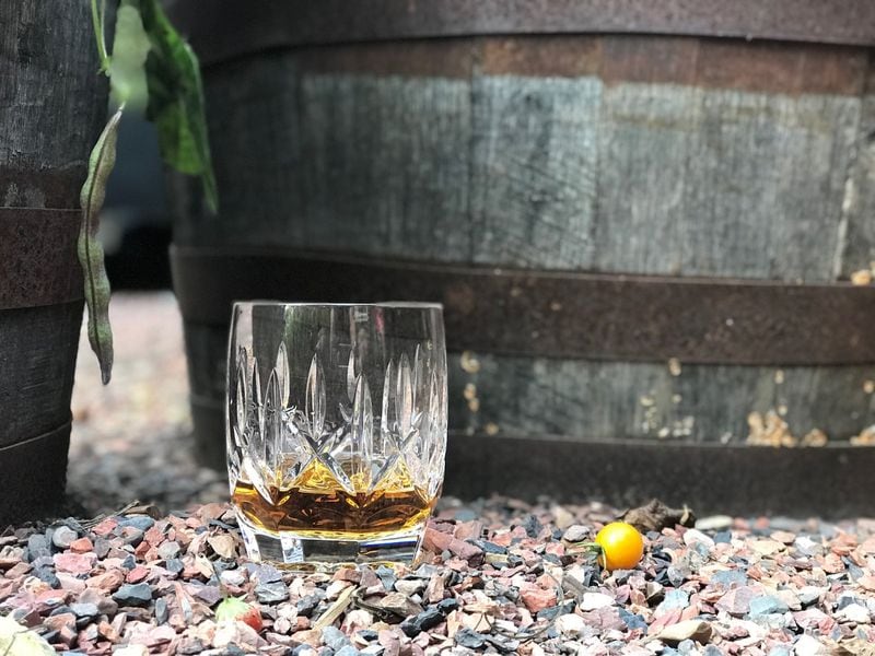 A glass of Jack Daniel’s whiskey amid the whiskey barrels that form a container garden in the backyard of AJC staff writer Rosalind Bentley. 