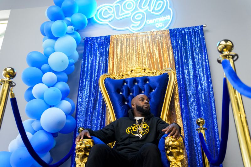 Cloud 9 Cannabis CEO and co-owner Sam Ward Jr. poses in a throne photo-op for customers, Saturday, April 13, 2024, in Arlington, Wash. The shop is one of the first dispensaries to open under the Washington Liquor and Cannabis Board's social equity program, established in efforts to remedy some of the disproportionate effects marijuana prohibition had on communities of color. (AP Photo/Lindsey Wasson)