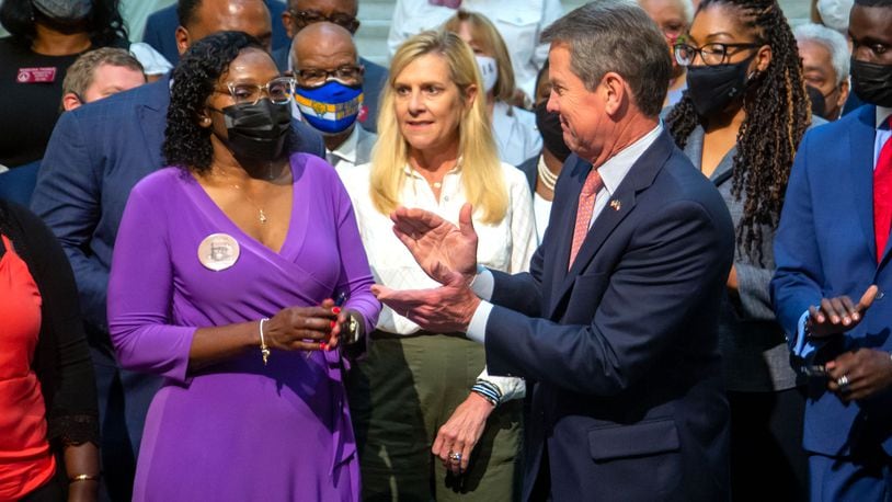 Wanda Cooper-Jones (left), mother of Ahmaud Arbery, stands with Gov. Brian Kemp after he signs House Bill 479, which overhauls Georgia's citizen's arrest law at the state Capitol Monday, May 10, 2021.   STEVE SCHAEFER FOR THE ATLANTA JOURNAL-CONSTITUTION