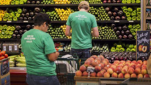 In this file photo, Instacart shoppers Jayme Romero, left and Adam Alfter check their iPhones to get the list of what customers want from a Whole Foods grocery store.