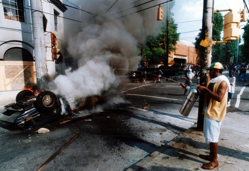 May 1, 1992: Someone tries to use a fire extinguisher on an overturned car set afire by demonstrators in the rioting after the Rodney King trial verdict. (W.A. Bridges Jr/AJC staff) 1992