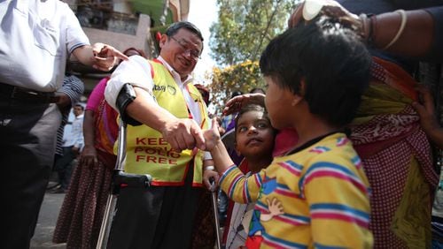Steve Stirling shakes hands with a child during a door-to-door polio vaccination campaign in Delhi.