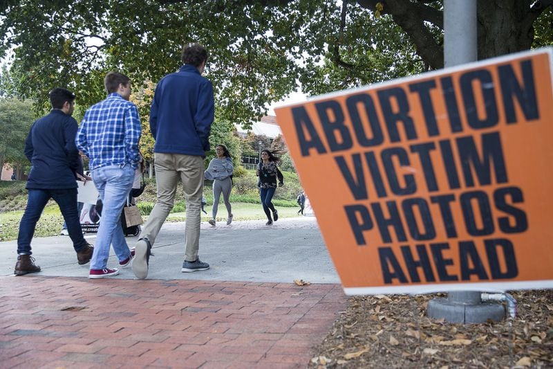 Students walk past graphic abortion photographs during a Cerated Equal organizational event at Georgia Tech’s campus in Atlanta on Monday. The Created Equal organization visited the campus with large photographs and video of aborted fetuses. ALYSSA POINTER/ALYSSA.POINTER@AJC.COM