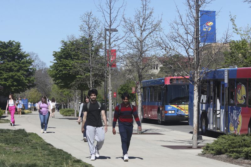 FILE - Students walk down Jayhawk Boulevard, the main street through the main University of Kansas campus, Friday, April 12, 2024, in Lawrence, Kan. A conservative quest to limit diversity, equity and inclusion initiatives is gaining momentum in state capitals and college governing boards, with officials in about one-third of the states now taking some sort of action against it. (AP Photo/John Hanna, File)