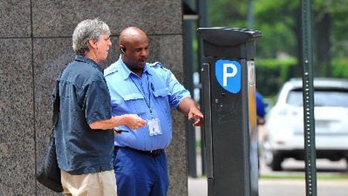 Kevin Brown with PARKAtlanta helps Bruce Goldsmith figure out the parking meter pay station in this August 2012 photo. Atlanta’s City Council tabled a vote Monday on a new parking enforcement vendor to replace PARKAtlanta, whose ticketing practices raised the ire of many motorists. BRANT SANDERLIN / BSANDERLIN@AJC.COM