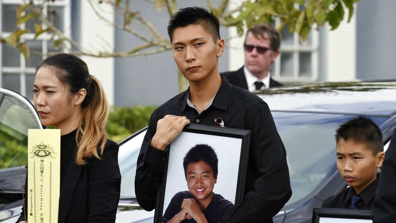 Jason Wang, center, holds a picture of his brother Peter, along with his younger brother, Alex, after his brother's funeral Tuesday, Jan. 20, 2018, at Kraeer Funeral Home in Coral Springs, Fla. Peter Wang, 15, was one of 17 people killed in a Valentine's Day mass shooting at Marjory Stoneman Douglas High School in Parkland.