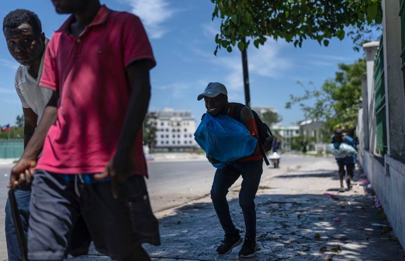 People run for cover as shots ring out near the National Palace in Port-au-Prince, Haiti, Monday, April 30, 2024. (AP Photo/Ramon Espinosa)