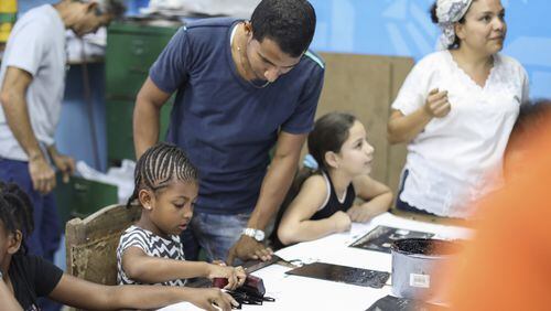 London Wyche (center) a third grader at the Green School, and Raquel Paulino, the school’s director (right) work on projects with staff and students from the Muraleando community arts center in Havana. The immersion school in East Point recently sponsored a trip to Cuba.