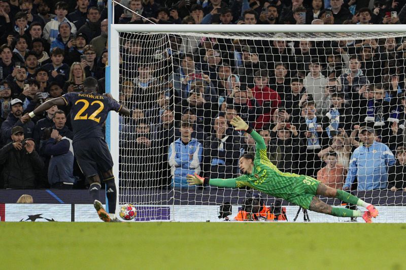 Manchester City's goalkeeper Ederson, right, fails to save the ball as Real Madrid's Antonio Rudiger scores the winning penalty during a penalty shootout during the Champions League quarterfinal second leg soccer match between Manchester City and Real Madrid at the Etihad Stadium in Manchester, England, Wednesday, April 17, 2024. (AP Photo/Dave Shopland)