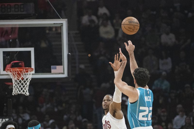 Charlotte Hornets' Vasa Micic (22) shoots over Cleveland Cavaliers' Isaac Okoro, second from right, during the first half of an NBA basketball game in Cleveland, Sunday, April 14, 2024. (AP Photo/Phil Long)