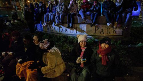 People try to keep warm while waiting for the live entertainment to start at Woodruff Park during the Peach Drop 2017, Sunday, Dec. 31, 2017, in Atlanta. BRANDEN CAMP / SPECIAL TO THE AJC