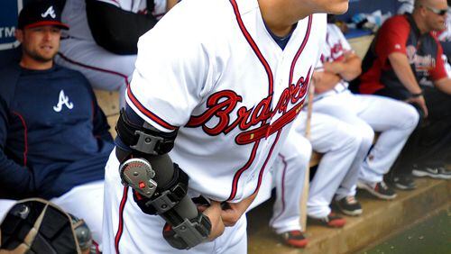 Atlanta Braves pitcher Kris Medlen wears an elbow brace on his right arm after season-ending Tommy John surgery as he waits during a rain delay in their exhibition baseball game against the team's minor league Future Stars Saturday, March 29, 2014, in Rome, Ga. (AP Photo/David Tulis)