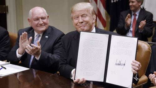 U.S. President Donald Trump signs the Executive Order Promoting Agriculture and Rural Prosperity in America as Agriculture Secretary Sonny Perdue looks on during a roundtable with farmers on Tuesday, April 25, 2017 in the Roosevelt Room of the White House in Washington, D.C. (Olivier Douliery/Abaca Press/TNS)