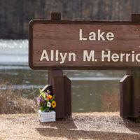 Family members laid flowers at the Lake Allyn M. Herrick sign in Athens at the University of Georgia on Friday, Feb. 23, 2024. Laken Riley, a 22-year-old, nursing student was found dead nearby on Thursday. (Jason Getz / jason.getz@ajc.com)