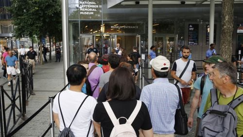 In this July 11, 2017 photo, visitors holding tickets line up at the entrance to the National September 11 Memorial and Museum in New York. Last winter the U.S. tourism industry worried about a "Trump slump," fearing that Trump administration policies might discourage international travelers from visiting the U.S. But statistics from the first half of 2017 suggest that the travel to the U.S. is robust and a number of sectors have reported increased international visitation, with one expert calling it a "Trump bump." The museum is among those reporting more international visitors this year compared to the same period in 2016. (AP Photo/Kathy Willens)