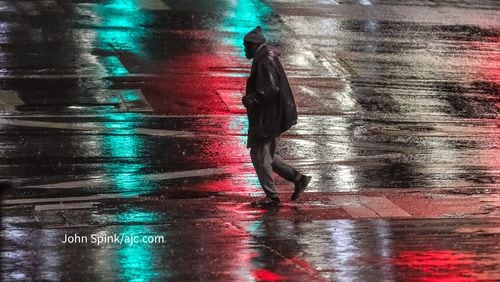 A man walks across the rain-slicked crosswalk at Peachtree and Decatur streets