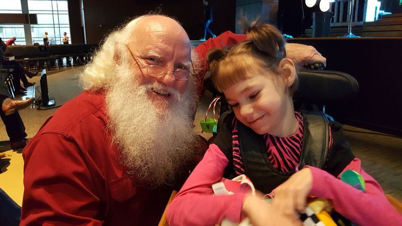 Santa Bill Odom brings cheer to children at his church, West Ridge Church in Dallas, Ga. Here he spends time with a girl with special needs. CONTRIBUTED