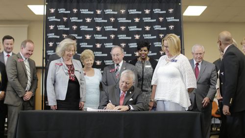 Surrounded by school officials and legislators, Gov. Nathan Deal signed this year’s budget with pay raises for teachers at at Lanier High School in Buford. BOB ANDRES / BANDRES@AJC.COM