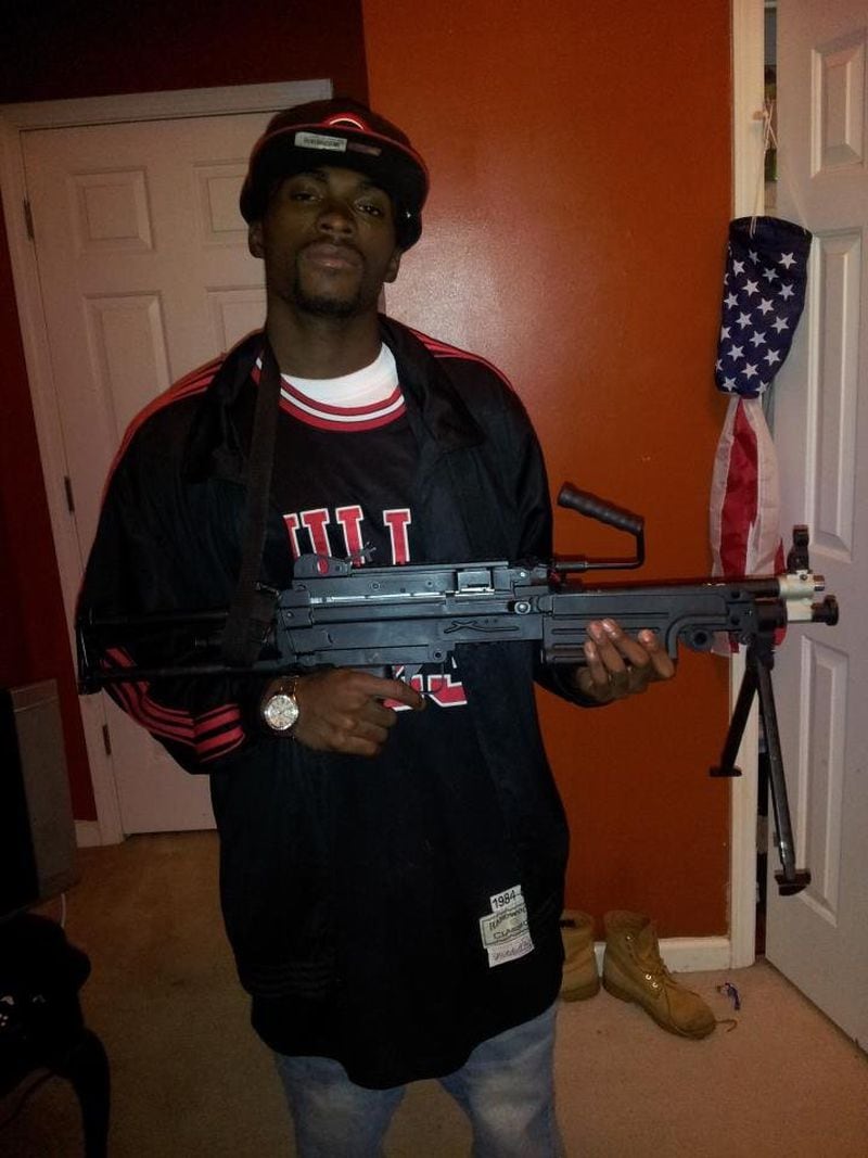 Edward Chadmon, who rapped under the name E-Thugga, poses with an assault rifle in a picture posted on his Facebook page.