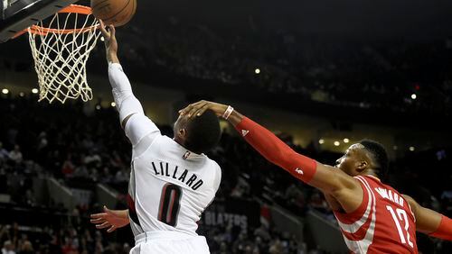 Portland Trail Blazers guard Damian Lillard (0) is fouled by Houston Rockets center Dwight Howard (12) as he drives to the basket during the second half of an NBA basketball game in Portland, Ore., Wednesday, Feb. 10, 2016. The Blazers won the game 116-103. (AP Photo/Steve Dykes)