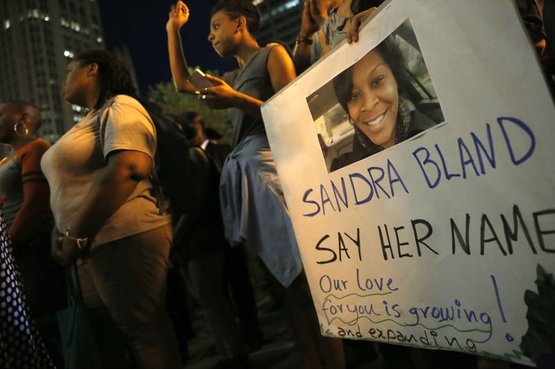 A demonstrator holds a Sandra Bland sign during a candlelight vigil July 28, 2015, near the DuSable Bridge on Michigan Avenue in Chicago. Bland, 28, died of apparent suicide in her jail cell three days after a July 10, 2015, traffic stop near the campus of Prairie View A&M University in Prairie View, Texas, where she attended college and had just gotten a new job. Former Texas state Trooper Brian Encinia, then 30, was fired and indicted for perjury in the case, but his perjury charge was later dropped in exchange for his never seeking another law enforcement job. Bland’s face became a prominent one in the Black Lives Matter movement following her death in police custody.