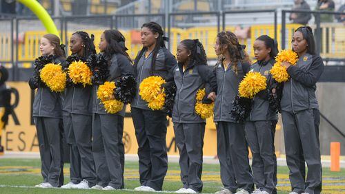 Kennesaw, Ga . -- A group of Kennesaw State cheerleaders link arms in the north end zone of Kennesaw State University's Fifth Thirds Bank Stadium during the National Anthem prior to the start of their game Saturday, November 11. They created a free-speech battle when they had kneeled during earlier games to join the national protest over how police have treated African Americans. Special/Daniel Varnado