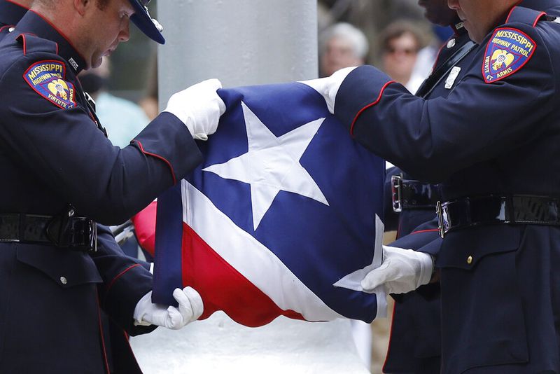 A Mississippi Highway Safety Patrol honor guard carefully folds the retired Mississippi state flag after it was raised over the Capitol grounds one final time. (AP Photo/Rogelio V. Solis)