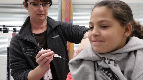 Kristen Earley, an RN at the Clark County Combined Health District, gives Braylinne Muhammad, 11, a flu shot Friday in the District’s offices. BILL LACKEY/STAFF