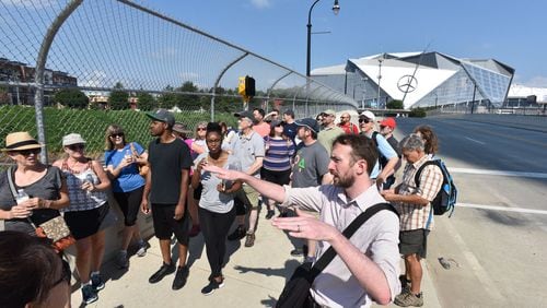 Kyle Kessler, community program manager of Center for Civic Innovation, leads a tour group near Mercedes-Benz Stadium on a south Downtown / Underground Atlanta Walking Tour on Saturday, August 5, 2017. HYOSUB SHIN / HSHIN@AJC.COM