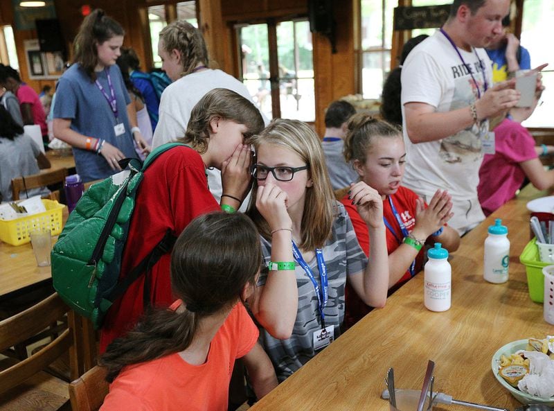 Bronco Reese whispers in the ear of Katherine McGuffin-Noll during lunch at Camp Braveheart at Camp Twin Lakes. Bronco took Katherine, who is a year older than he is, to the dance last year. This year, she graduated to another group attending a separate event. CURTIS COMPTON / CCOMPTON@AJC.COM