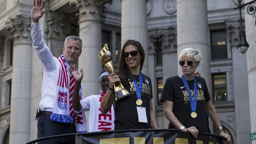 Carli Lloyd holds the World Cup trophy as she and other members of the U.S. women's national soccer team paraded down Broadway in New York, July 10, 2015. It's the first time the city has honored a women's sports team with a ticker-tape parade. At left is Mayor Bill de Blasio, at right, Megan Rapinoe. (Mark Kauzlarich/The New York Times)