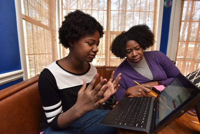 Paula Richards-Bell, eighth-grade teacher at Jordan Middle School, helps her daughter Olivia Bell, 11, who is a sixth-grader at Jordan Middle School, with her digital learning day assignment at their home in Lawrenceville on Thursday, Jan. 18, 2018. Gwinnett County schools, the largest school district in the state, launched its digital learning program on Jan. 8, when the threat of ice and frigid temperatures led administrators to close schools. HYOSUB SHIN / HSHIN@AJC.COM