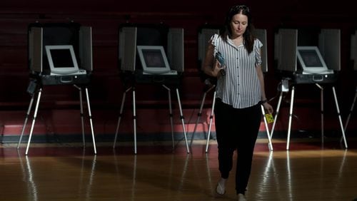 Sunlight streams through the windows of the gym as Dawn Churi walks away from the voting booths after voting Tuesday during the Georgia runoff election at Henry W. Grady High School in Atlanta. (JASON GETZ/SPECIAL TO THE AJC)