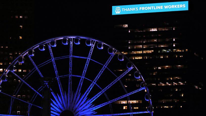 April 9, 2020 Atlanta: A building on the skyline bears the message thanks frontline workers behind the Skyview Ferris Wheel bathed in blue as part of an initiative to salute essential workers on the frontlines of the coronavirus pandemic on Thursday, April 9, 2020, in Atlanta. The Light It Blue event includes more than 150 major sports and entertainment venues and historic landmarks and buildings across the United States.  Curtis Compton ccompton@ajc.com