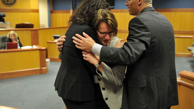 Stacey Kalberman, center is hugged by her attorney Kimberly Worth, left, and husband Neil after winning a whistle blower suit against the state ethics commission. The former state ethics commission executive director sued after she claimed she was forced from her position after investigating Gov. Nathan Deal's campaign.