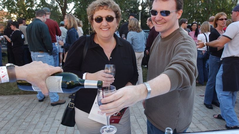 Leona Davis, left, of Atlanta, and Carl Black, right, of DeKalb County, enjoy the day as Black tries a sample of a California merlot from the Grape Expectations table Saturday, November 6, 2004 at the 3rd Annual Decatur Wine Festival on the square in downtown Decatur.