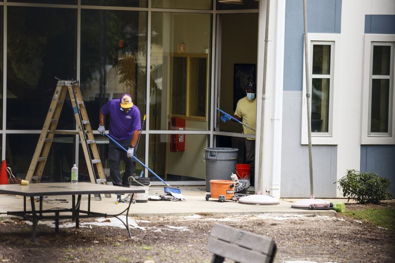 Workers sweep up glass and debris from a broken window at At-Promise Youth Center on Friday, May 27 2022. (Natrice Miller / natrice.miller@ajc.com)

