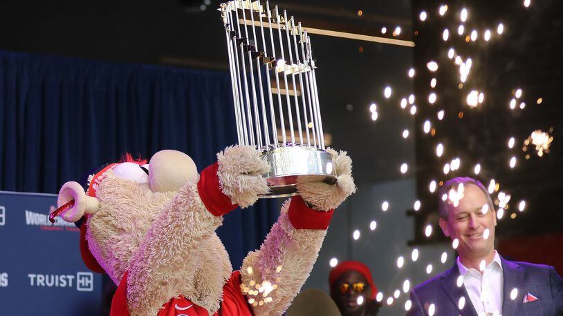 Atlanta Braves mascot Blooper shows the Commissioner’s Trophy to the crowd while Braves President and CEO Derek Schiller reacts during the first stop of the World Champions Trophy Tour on Tuesday at Colony Square in Midtown. (Miguel Martinez for The Atlanta Journal-Constitution)