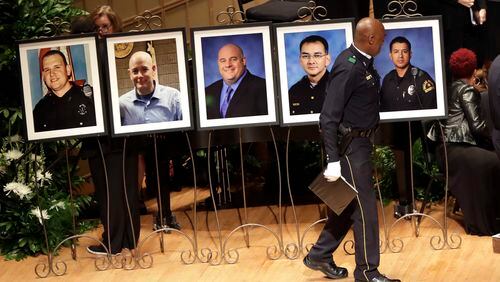 A member of the Dallas Police Choir passes the portraits of five fallen officers prior to a memorial service at the Morton H. Meyerson Symphony Center, Tuesday, July 12, 2016, in Dallas. Five police officers were killed and several injured during a shooting in downtown Dallas last Thursday night. (AP Photo/Eric Gay)