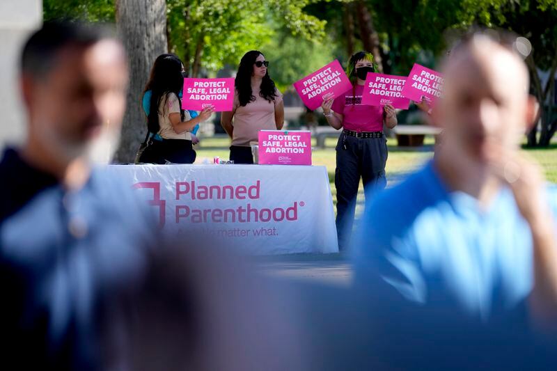 Anti-abortion supporters kneel as abortion supporters holds signs in the background, Wednesday, May 1, 2024, at the Capitol in Phoenix. Democrats secured enough votes in the Arizona Senate to repeal a Civil War-era ban on abortions that the state's highest court recently allowed to take effect. (AP Photo/Matt York)