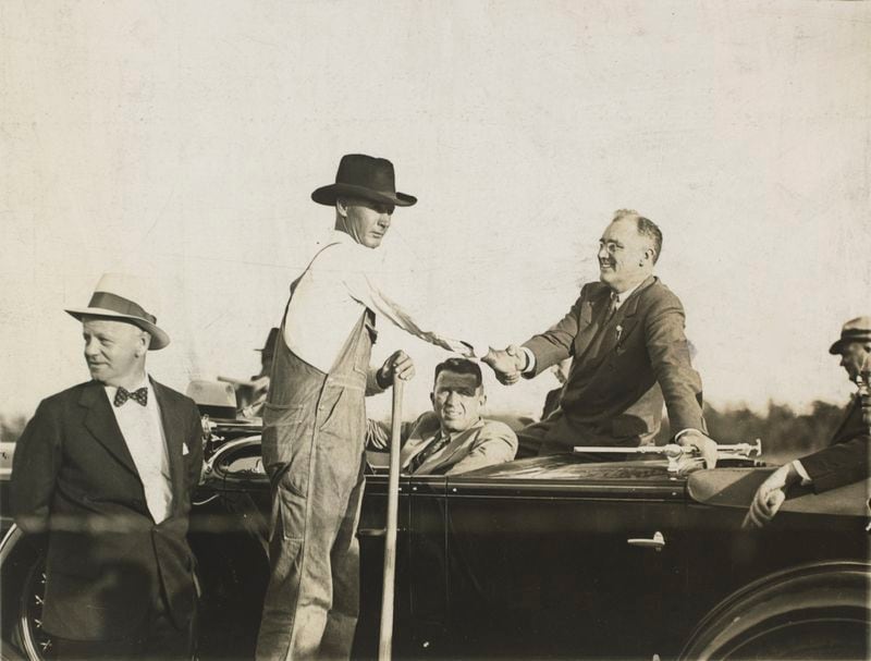 View of presidential candidate Franklin Delano Roosevelt shaking hands with an unidentified farmer during a campaign visit to Georgia in October 1932. Alvin L. Belle Isle,  a prominent Atlanta businessman, is the driver beneath the handshake. Photo credit: Kenan Research Center at the Atlanta History Center.