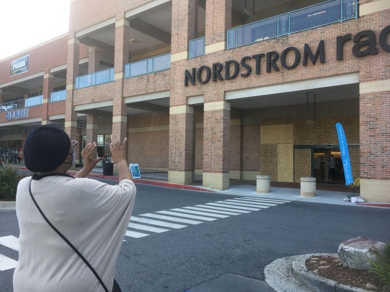 Dunwoody resident Diana Hines takes a photo of the boarded up Nordstrom Rack near Perimeter Mall on Tuesday morning.